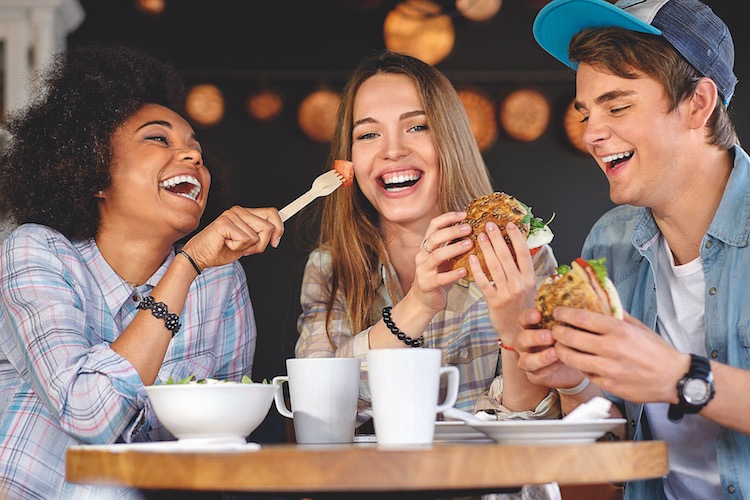 Cheerful multiracial friends eating in a cafe