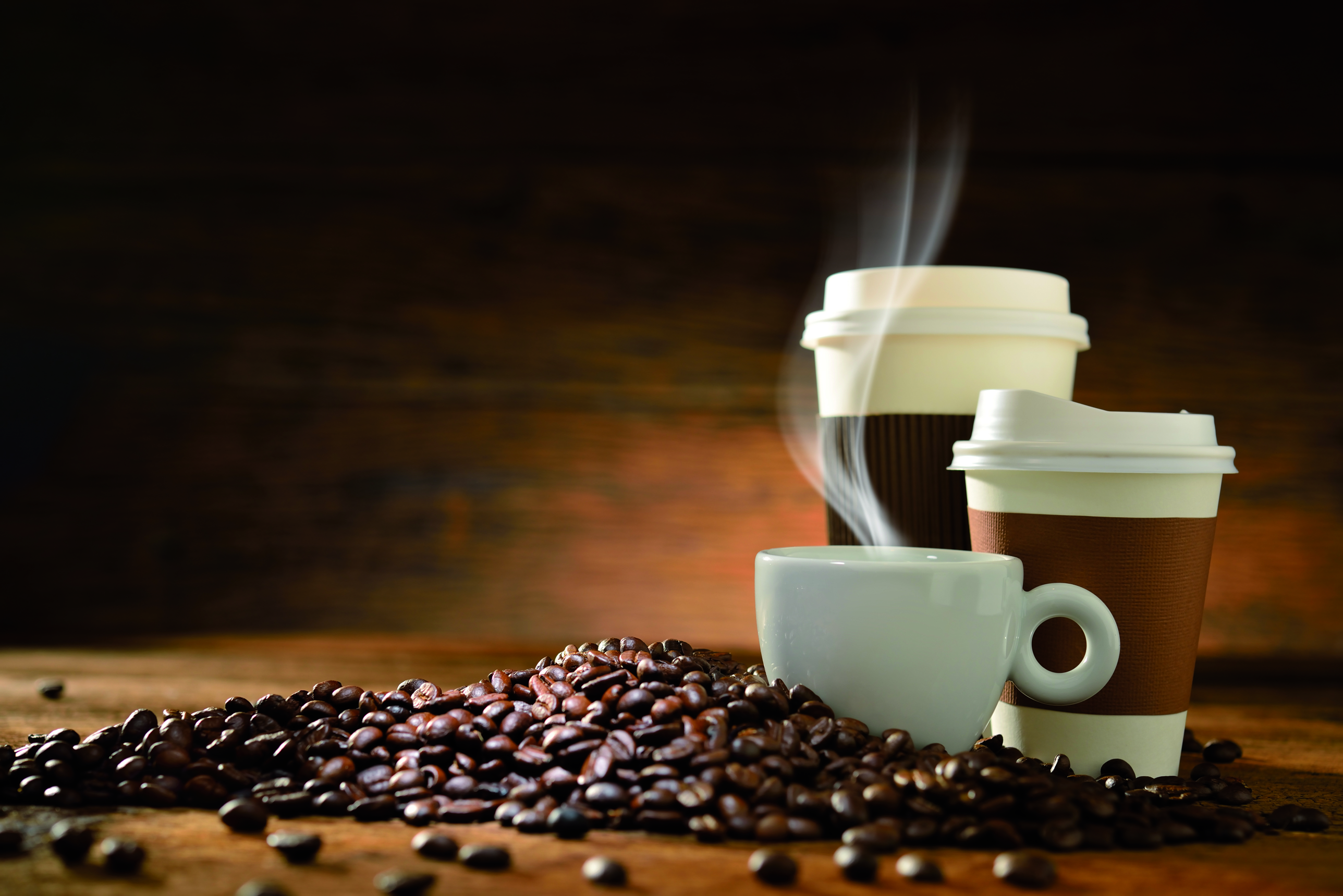 Kaffebohnen, eine Tasse Kaffee und zwei Take-Away-Kaffeebecher