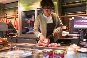 Verkäuferin schneidet ein Stück Fleisch zum Verkauf zurecht