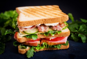 Sandwich mit Bacon, Salat, Käse, Gurke, Schinken und mehr